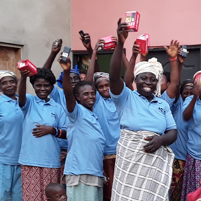 A group of women in blue shirts holding up red boxes