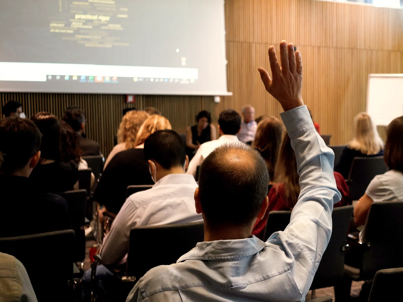 A group of people watching a conference presentation