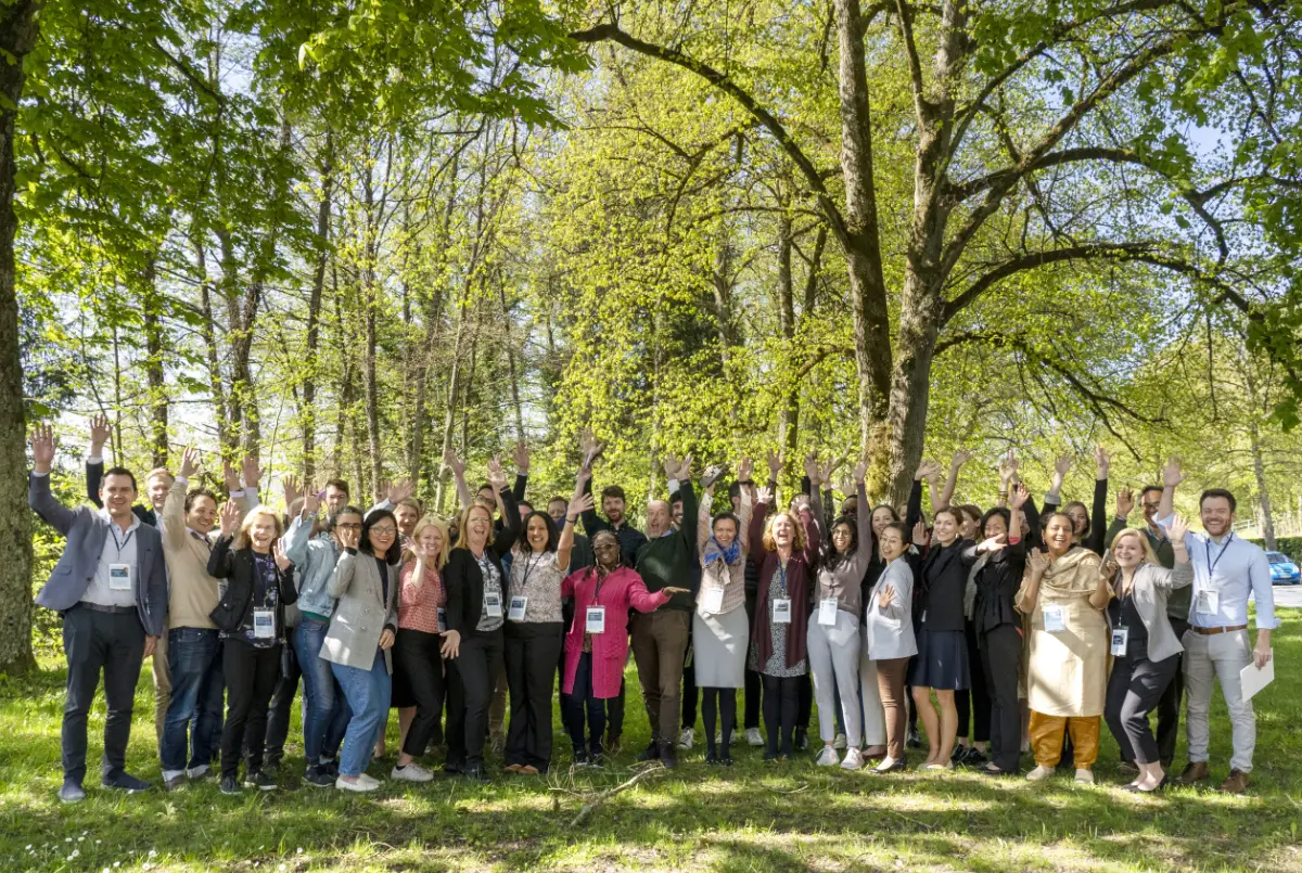 A group of people with raised hands standing under trees