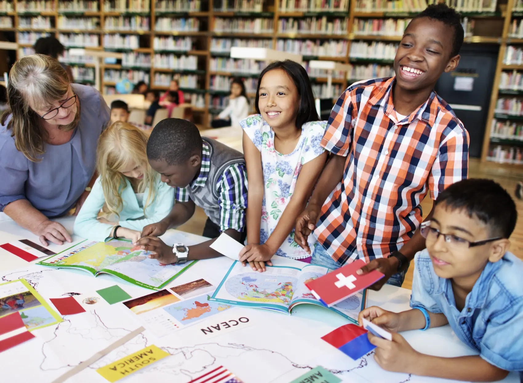 Smiling kids work on a school desk covered in world flags